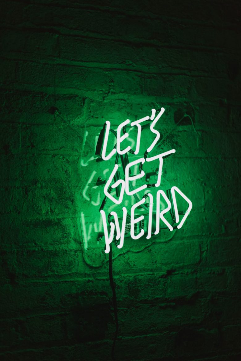 Let's get weird neon sign on brick wall