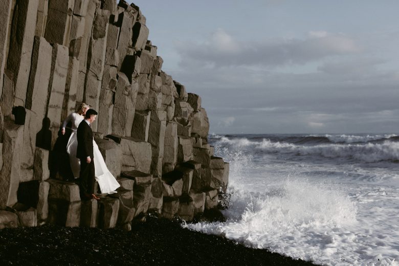 Bride and groom near rocky cliff and ocean