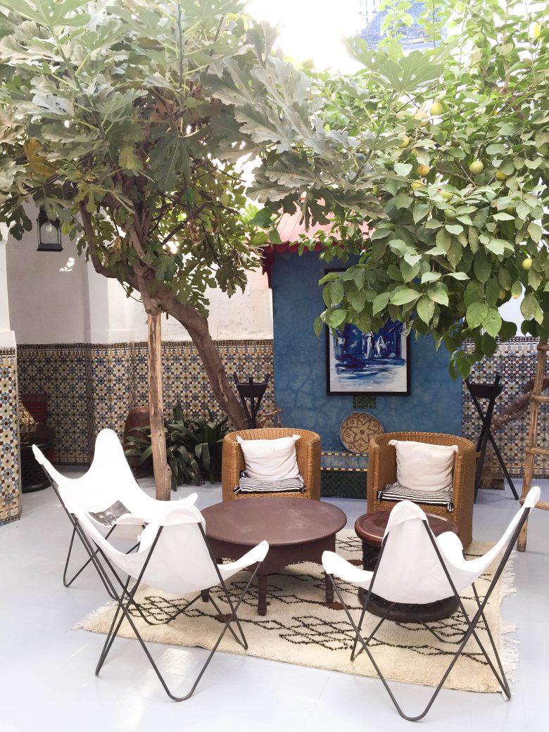 chairs and trees in the center of a moroccan courtyard