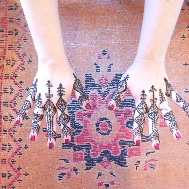 traditional henna hands seen over Moroccan carpet