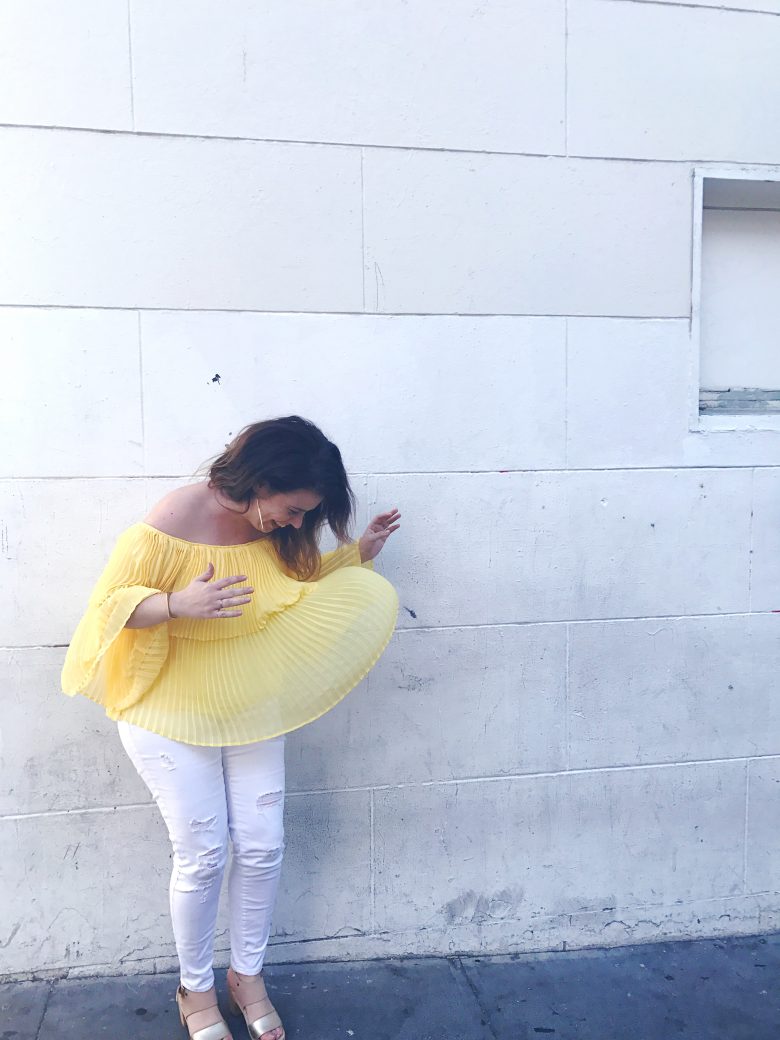 Author in front of white wall with yellow shirt blowing in the wind