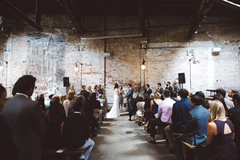 Wedding ceremony in industrial space with brick wall
