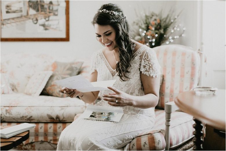 bride sitting in chair, reading a letter, smiling
