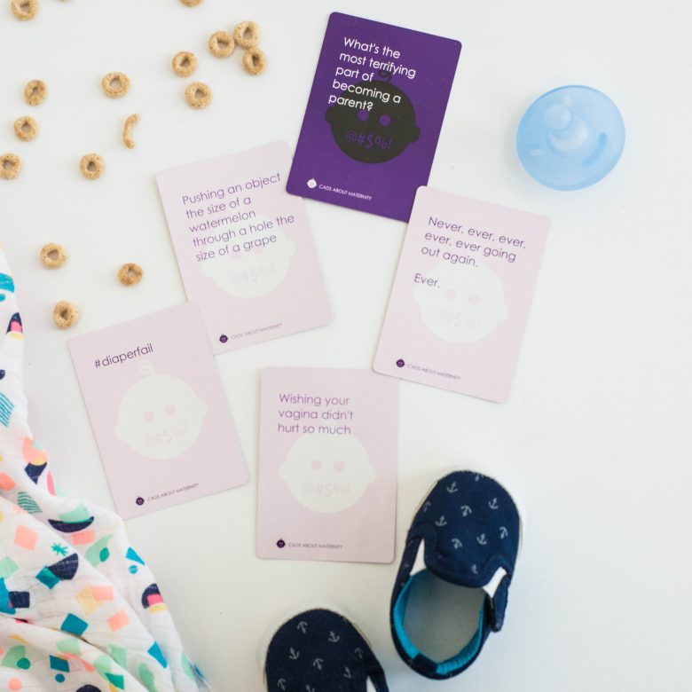 cads about maternity, cheerios, brightly colored baby blanket, pacifier, and navy baby shoes
