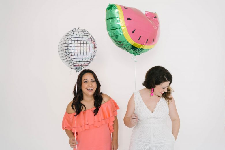 Two women holding balloons, lauging