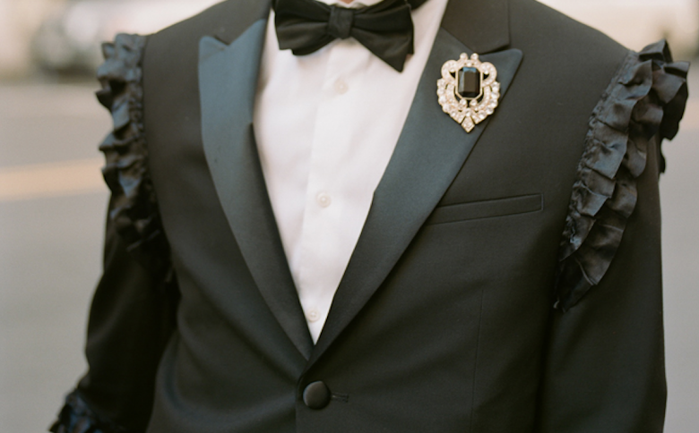 Tux jacket with shoulder seam ruffles and bejeweled broach