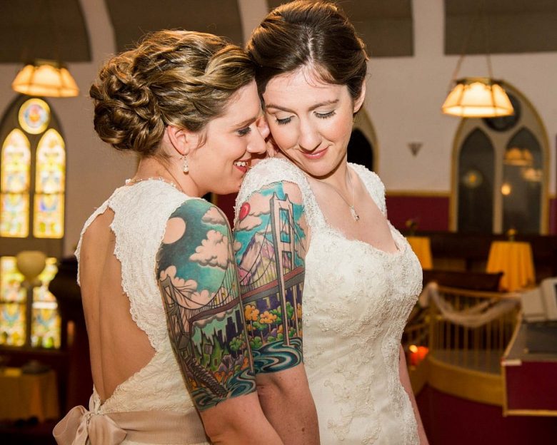 Two brides with bridge cityscape couple tattoos on upper arms