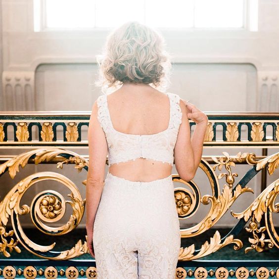 woman in white lace pants and crop top from behind with short wavy blond hair for a wedding hairstyle