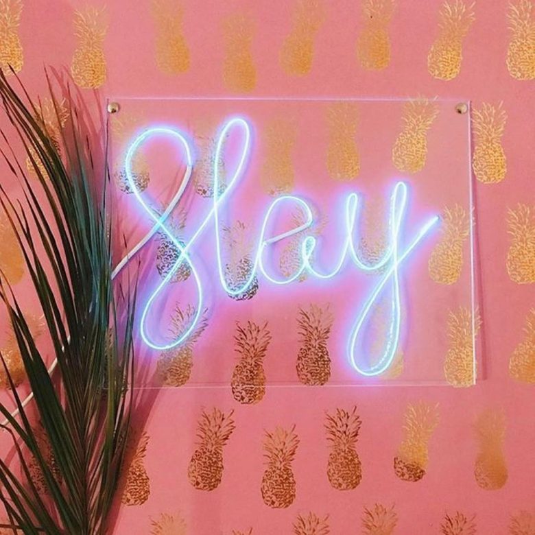 Neon sign of the word Slay on a pink wall