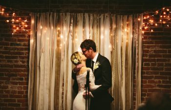 Couple kissing in front of a wedding backdrop