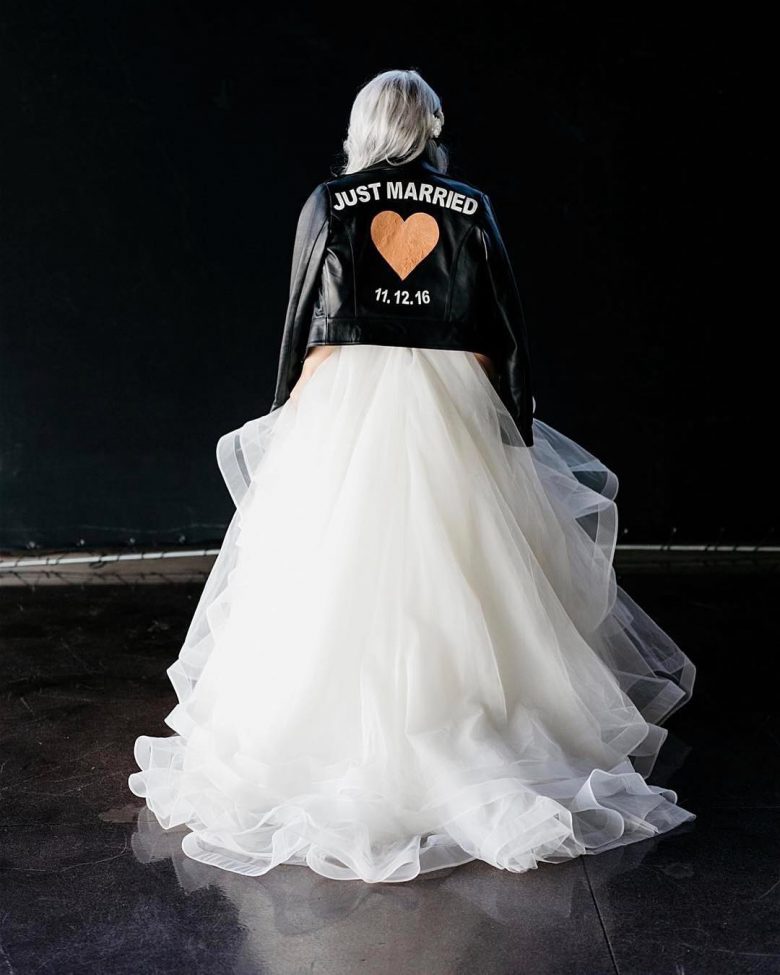 bride in wedding dress wearing leather jacket that says "Just Married" with a heart and the date 11.12.16 on it