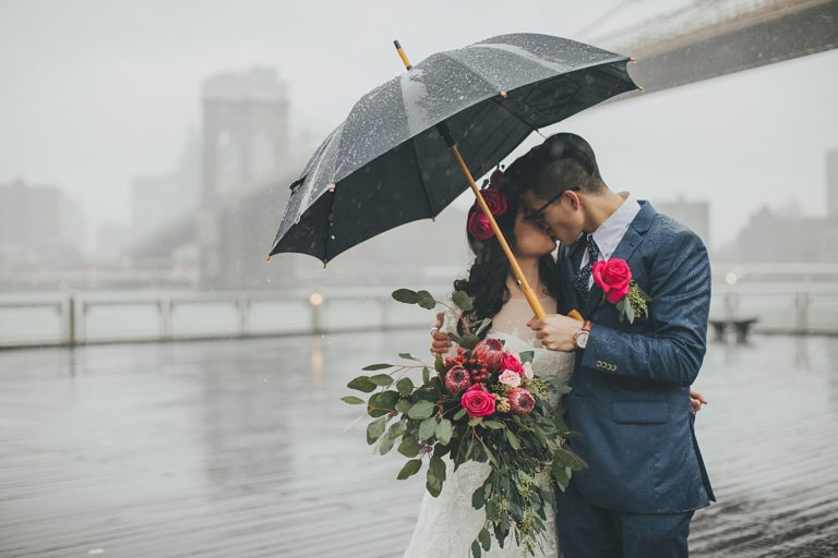 As the rain comes down in New York, a couple huddles under an umbrella and steals a sweet kiss 