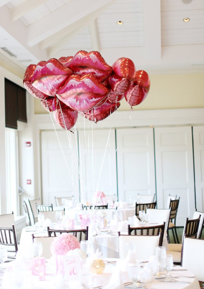 Bright tablescape with bouquet of lip balloons, table decorated with pink, gold, and white