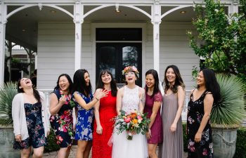 A bride smiles and laughs as she is surrounded by her wedding party