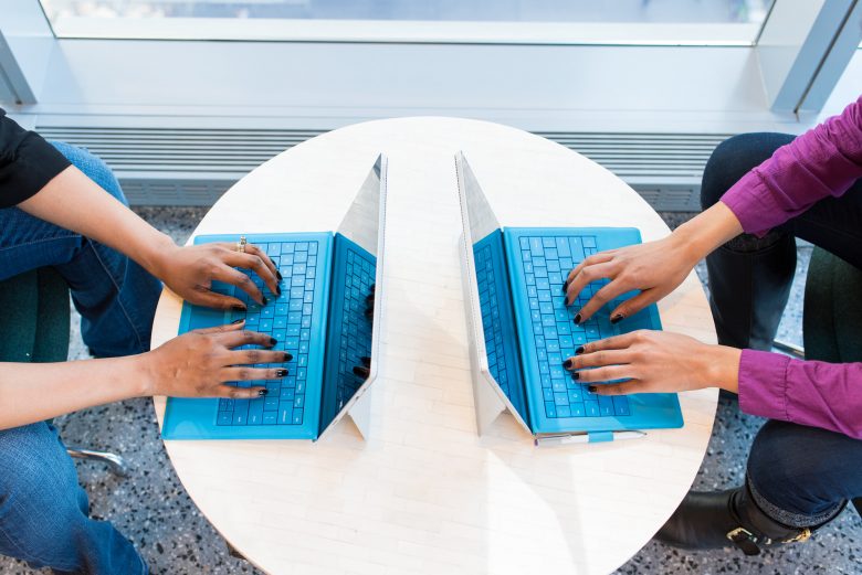 two women typing on blue keyboards