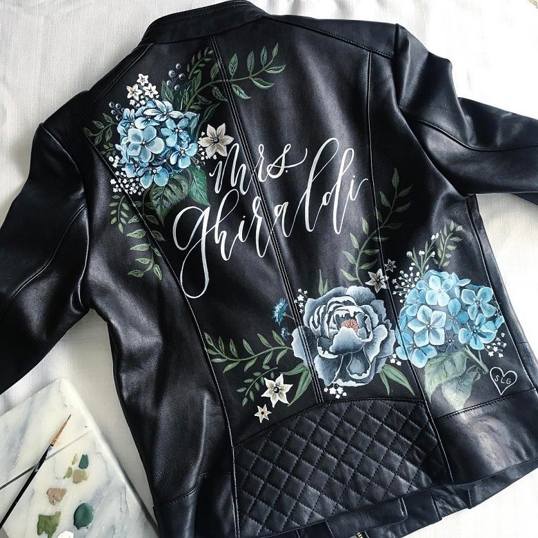 A black leather jacket with a flower prints and calligraphy 