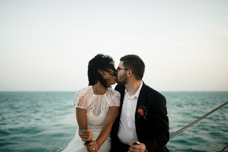Bride and groom kissing on boat in the water