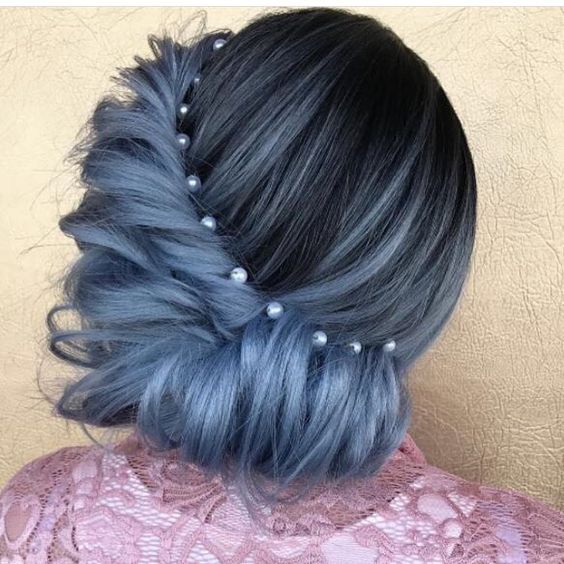 woman with dark and grey-blue hair with a side roll from front to back with pearl accents