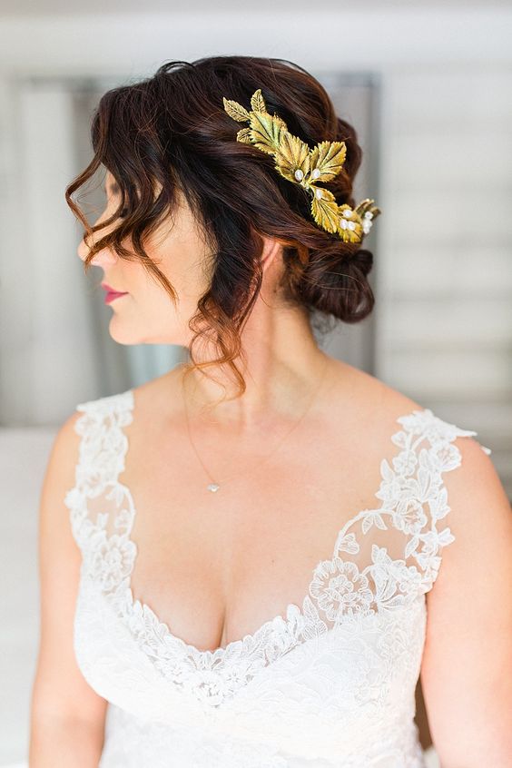 woman with curls loosely gathered at nape with gold leaf hair accessory for a wedding hairstyle