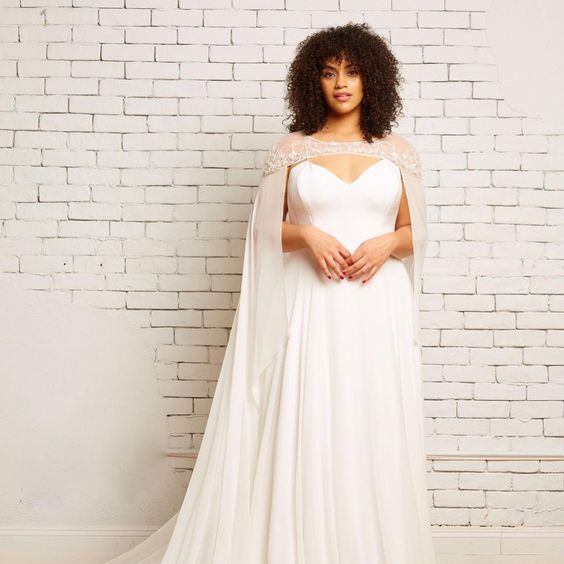 woman in wedding dress and cape with shoulder-length natural curly hair and bangs