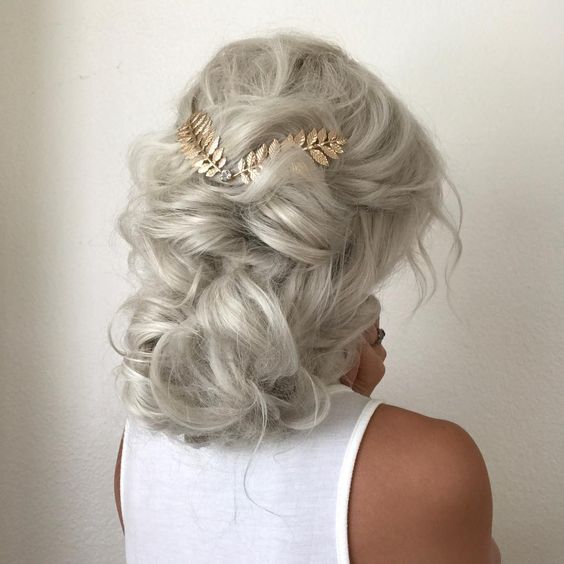 Woman with curly platinum hair gathered back with with gold fern hair accessory