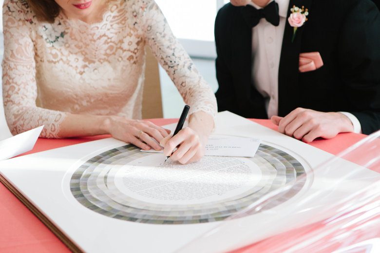 Closeup of a couple signing their ketubah