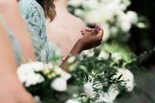 Viewpoint down a line of bridemaids, focus on one of their hands