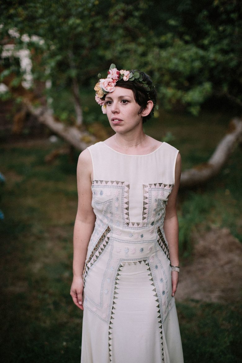 a short haired bride stands in a wooded back yard