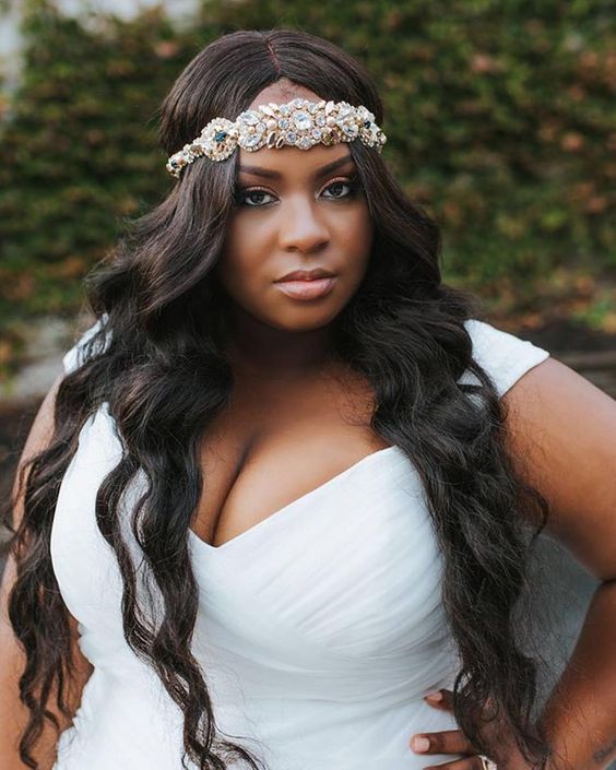 woman with long curled dark hair parted in the middle with ornate jeweled headband across forehead for a wedding hairstyle