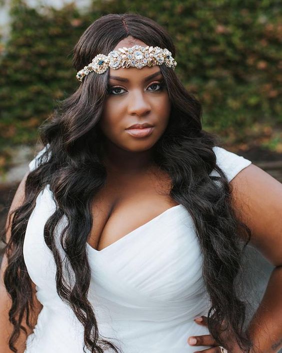 woman with long curled dark hair parted in the middle with ornate jeweled headband across forehead