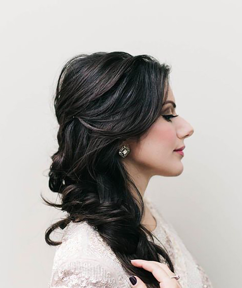 woman with long dark hair loosely pulled back and cascading in loose curls down her shoulder