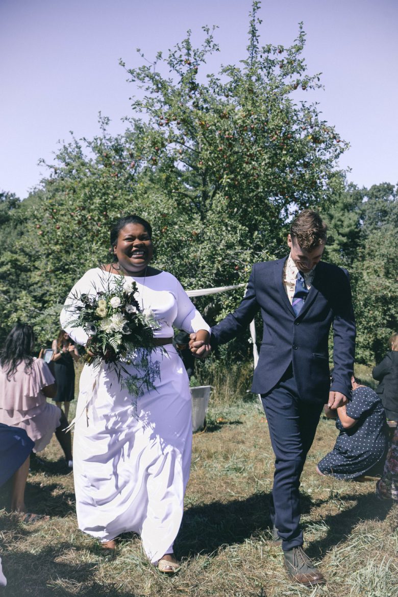 a bride and groom make their recession holding hands with the biggest smiles you've ever seen