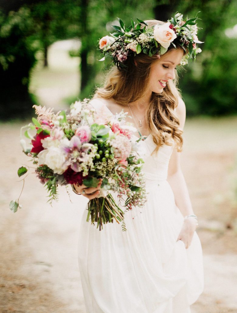 a bride smiles as she walks carrying her dress train and flower bouquet