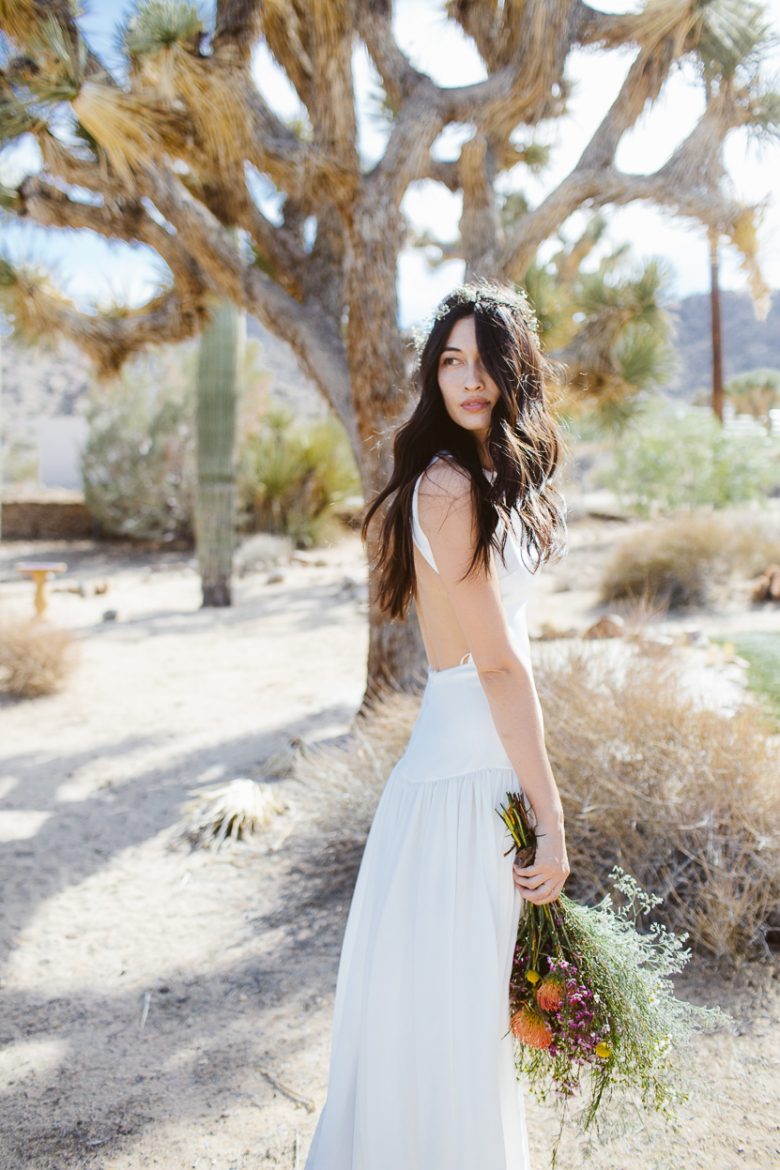a bride looks back over her shoulder as she stands among the ancient joshua trees