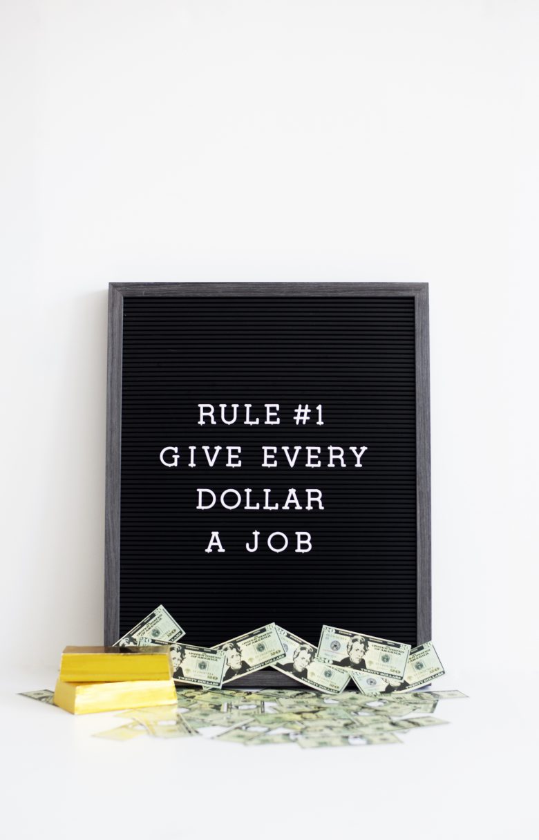 Message board with loose dollar bills at the bottom. Message says Rule Number one, give every dollar a job.