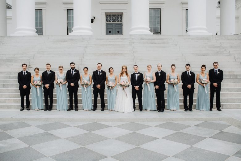 A wedding party stands in front of courthouse steps
