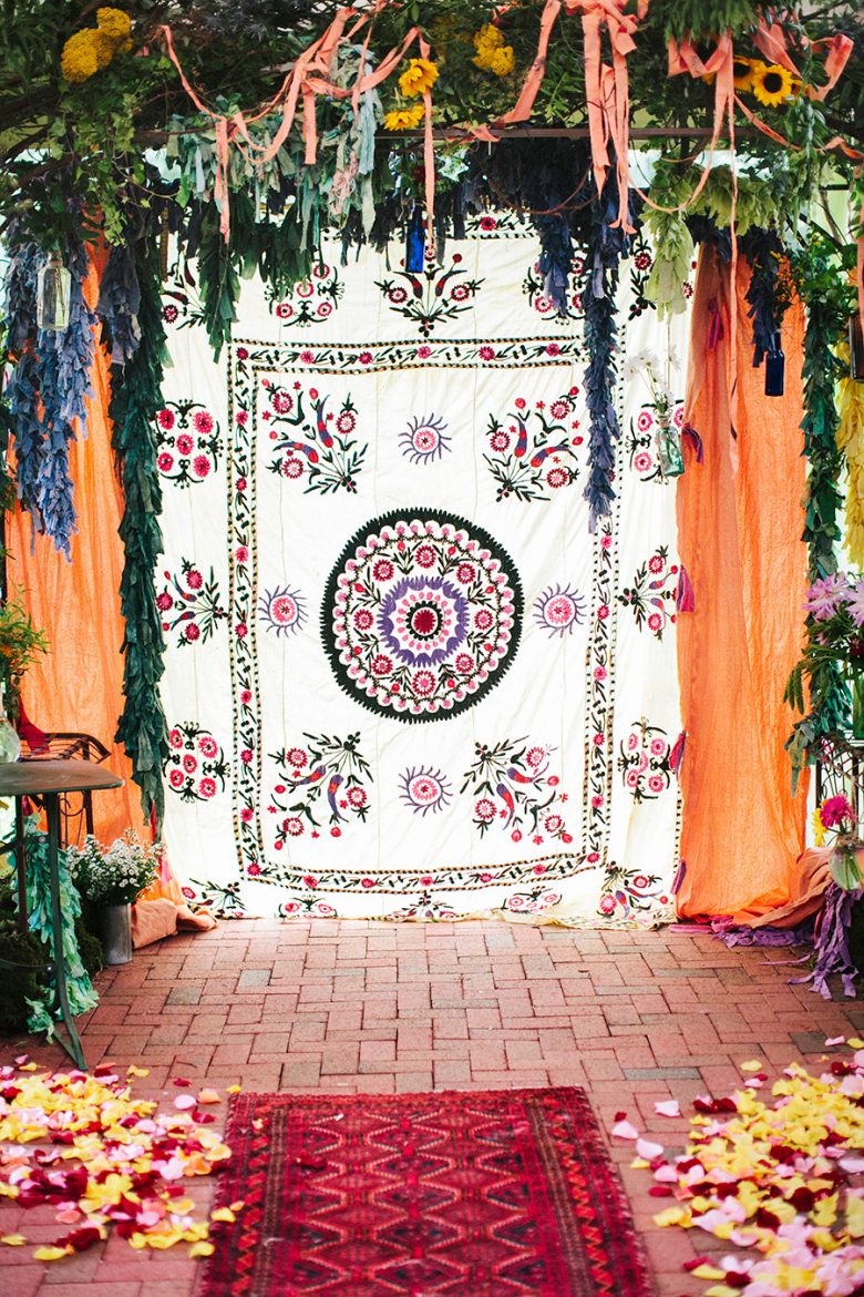 Wedding ceremony area with wall tapestry backdrop and rugs as wedding decorations