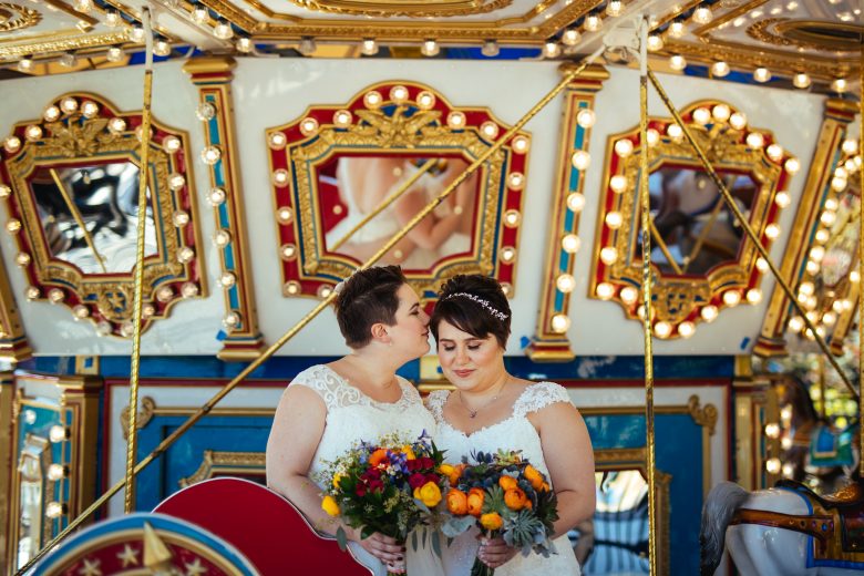 bride kissing her bride's cheek on a carousel 