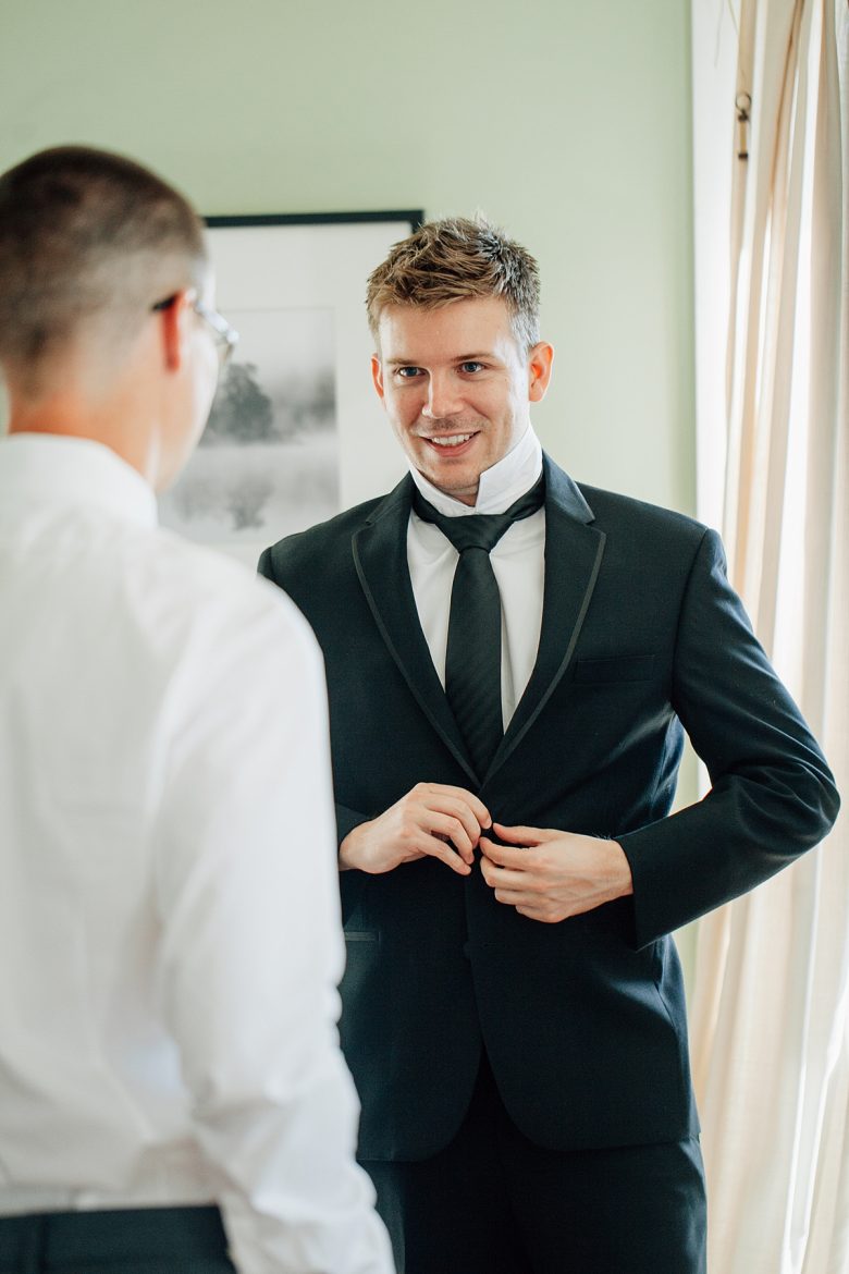 Man getting ready for his wedding, buttoning his suit jacket
