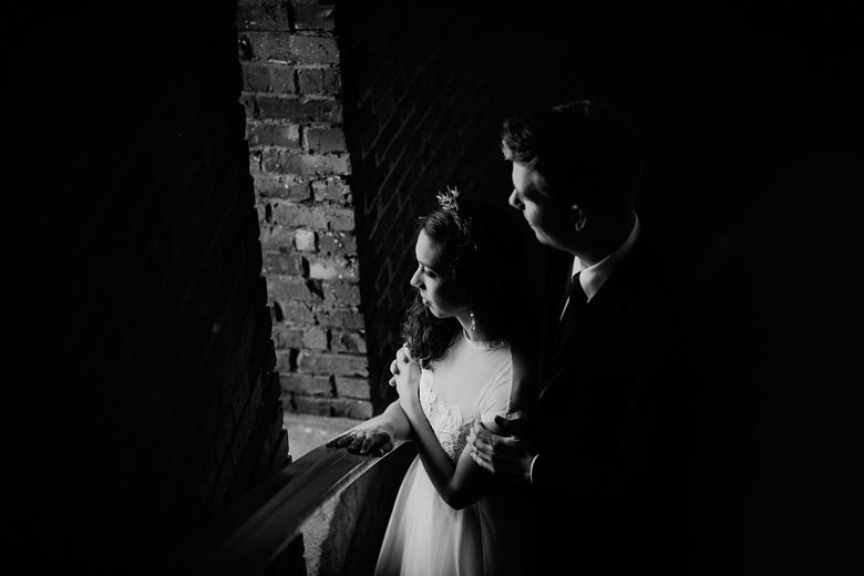 bride and groom look out a window. black and white photo.