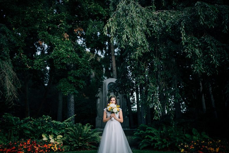 a bride stands silently by herself in the forest