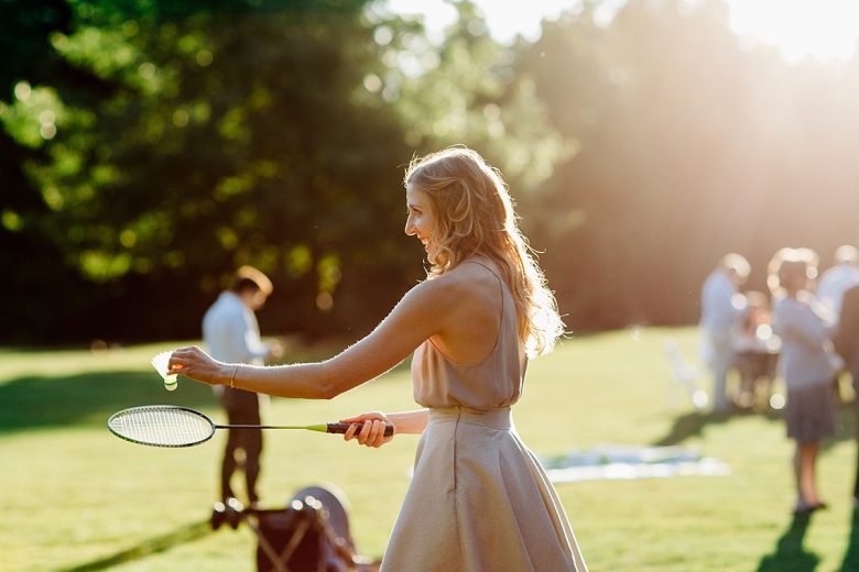 a wedding guests plays badminton as the sun shines behind her