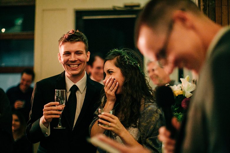 bride and groom laughing at best man's speech