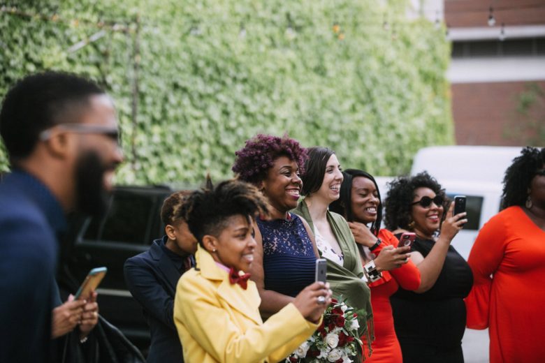 Wedding guests at a ceremony cheer on the couple with big smiles