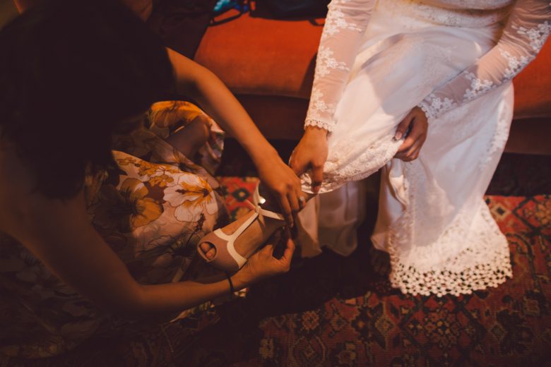 Closeup of a bride getting her shoes put on