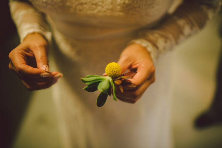 Close up of a bride holding her groom's boutonniere 
