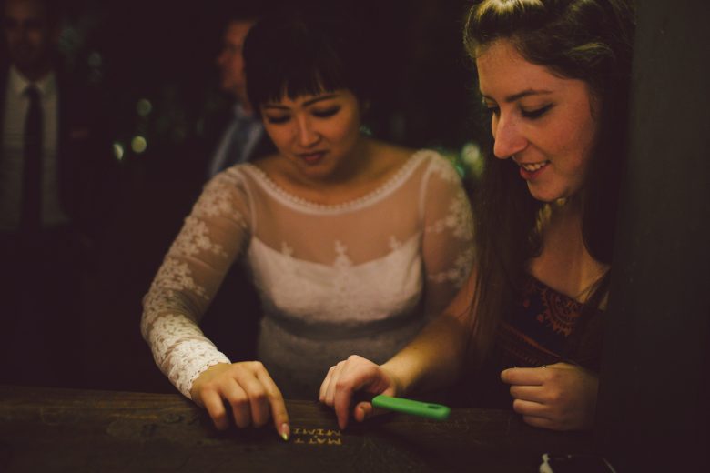bride shows a guests how to carve her name and sign the wooden guests book