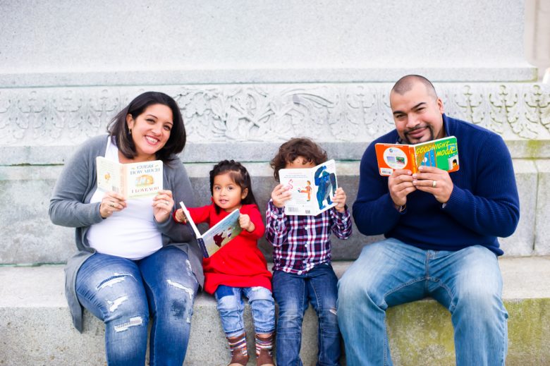 family of four reads board books on a marble step