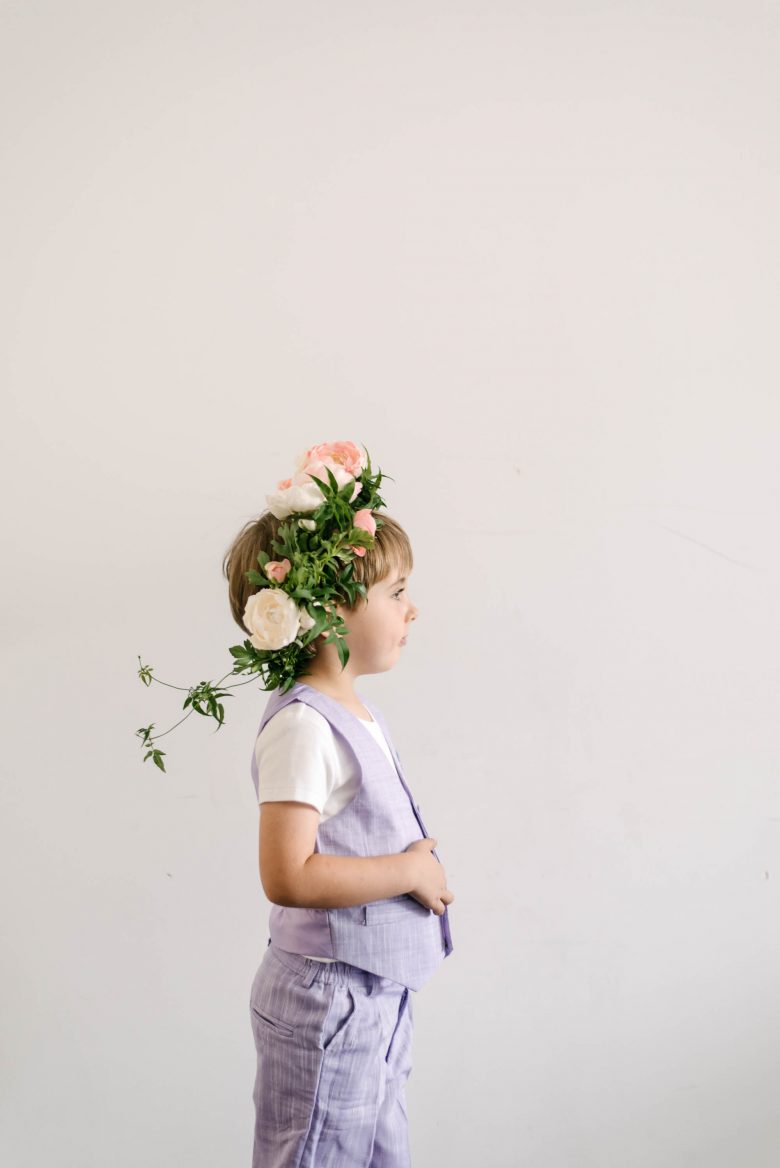 profile photo of a young boy wearing a lavender vest and pants with a flower crown