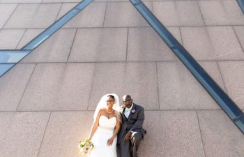 A wedding couple lean against a wall